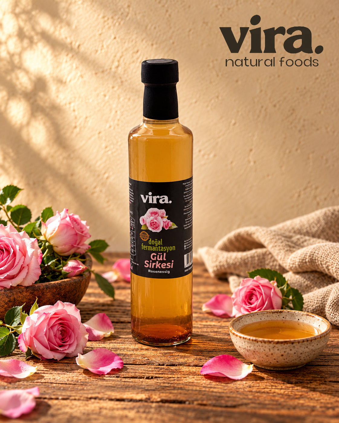 vira. Rosenessig natürlich fermentiert in Glasflasche mit rosa Rosen auf Holztisch