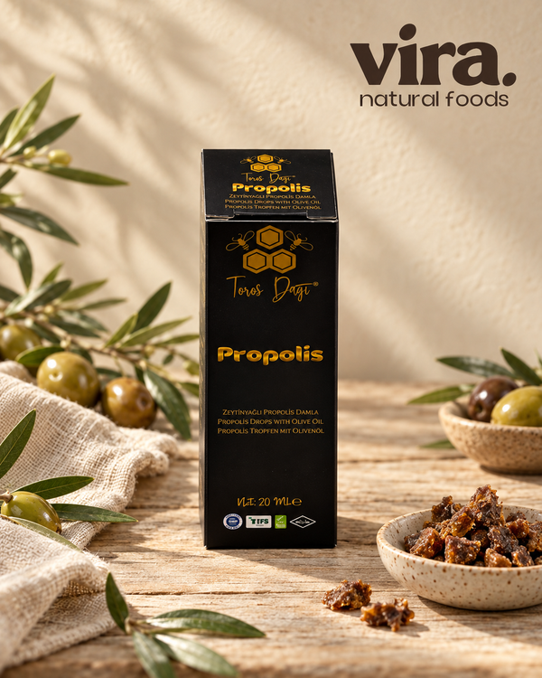 Toros Dağı Propolis Tropfen mit Olivenöl 20ml in schwarzer Faltschachtel neben Oliven und Propolis