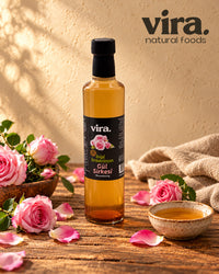 vira. Rosenessig natürlich fermentiert in Glasflasche mit rosa Rosen auf Holztisch