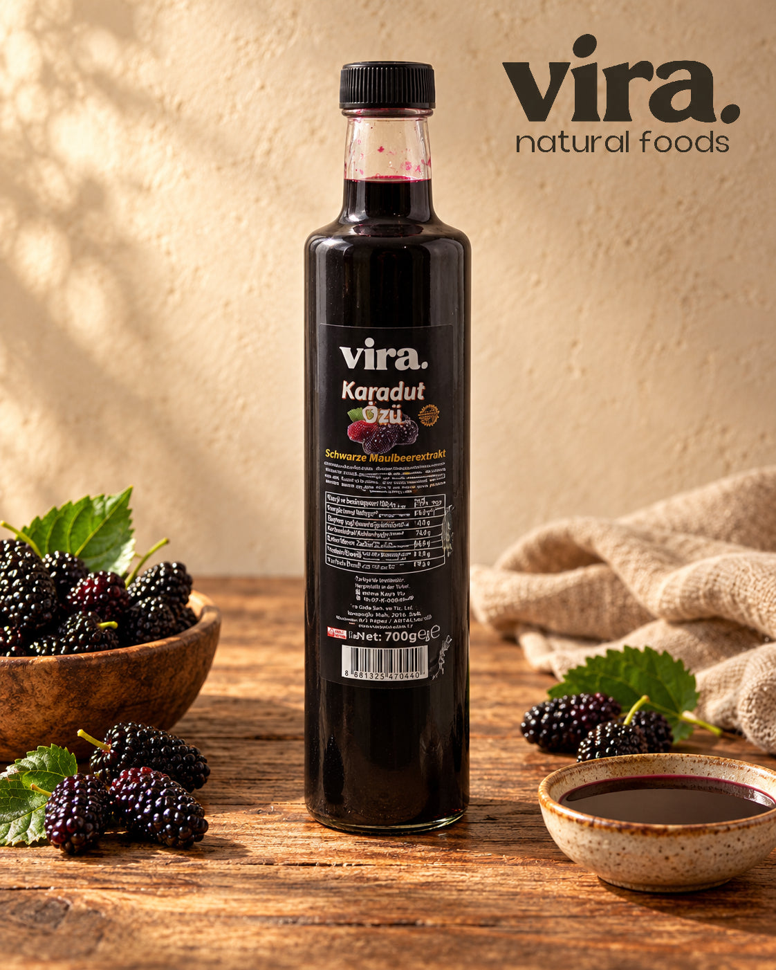 vira. Schwarzer Maulbeerextrakt 700g in Glasflasche mit frischen schwarzen Maulbeeren auf einem Holztisch