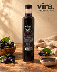 vira. Schwarzer Maulbeerextrakt 700g in Glasflasche mit frischen schwarzen Maulbeeren auf einem Holztisch