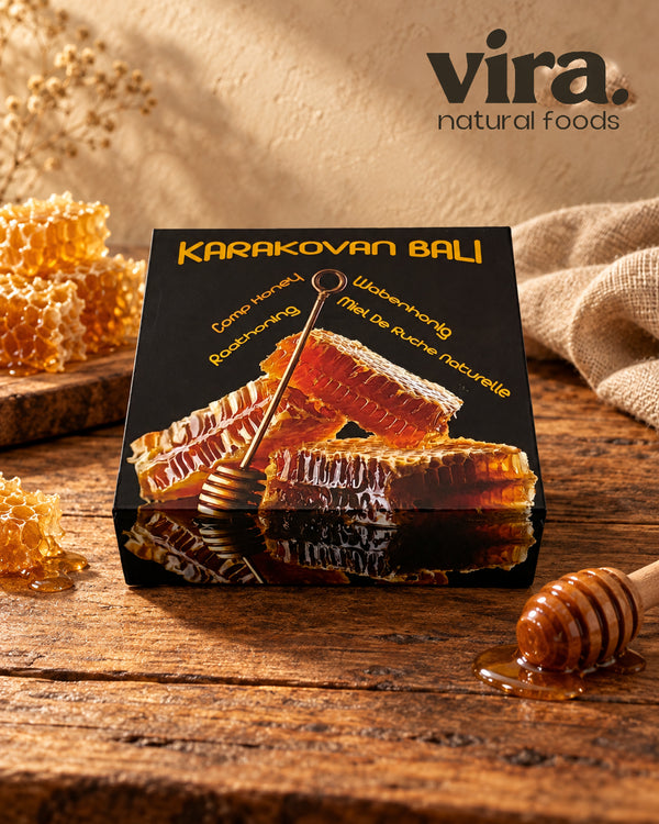 vira. Wabenhonig in schwarzer Box mit Honigwaben und Honiglöffel auf einem Holztisch