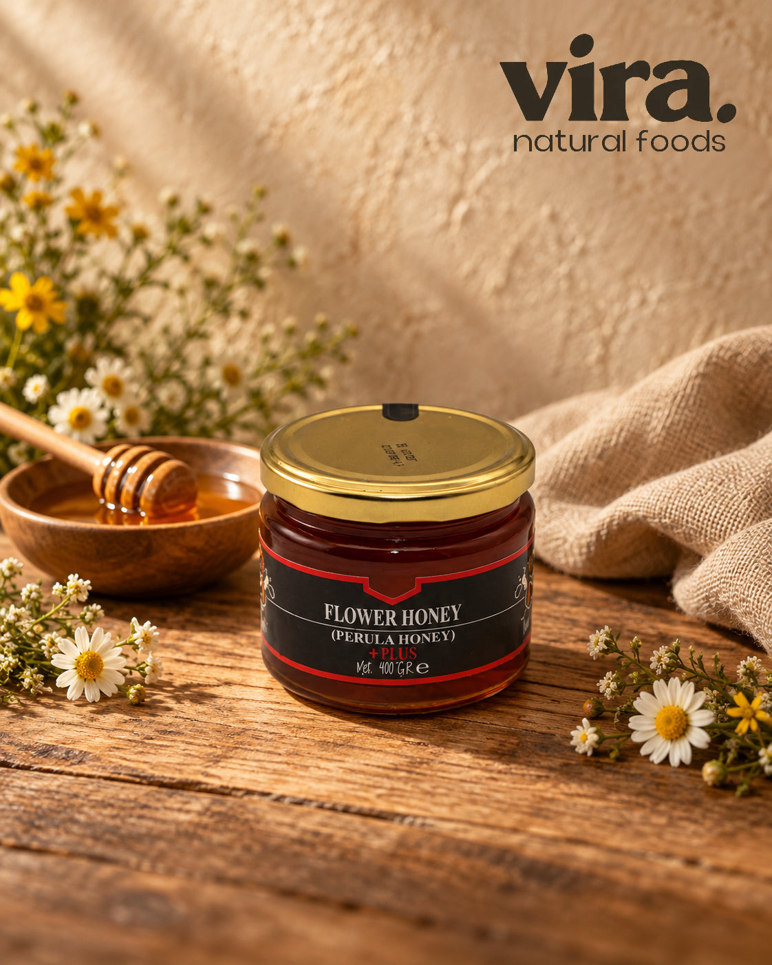 vira. Blütenhonig (Perula Honig) Plus im 400-g-Glas mit Goldetikett auf Holztisch mit Kamillenblüten
