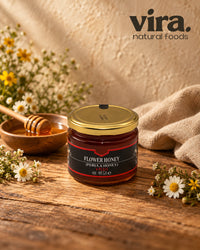 vira. Blütenhonig (Perula Honig) Plus im 400-g-Glas mit Goldetikett auf Holztisch mit Kamillenblüten